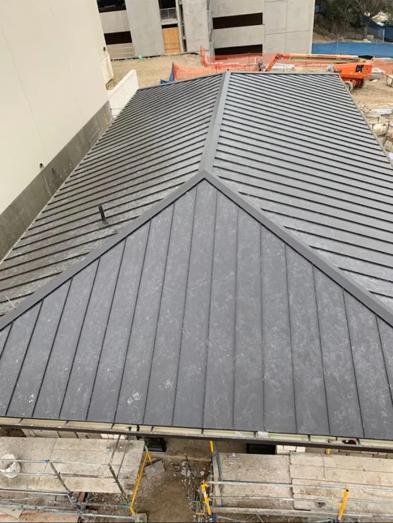 Commercial metal roof construction with crane equipment in Firestone